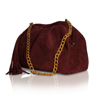 Borsa pasticcino Soley in camoscio bordeaux, vista di tre quarti, con catena dorata e nappina laterale con frange.
